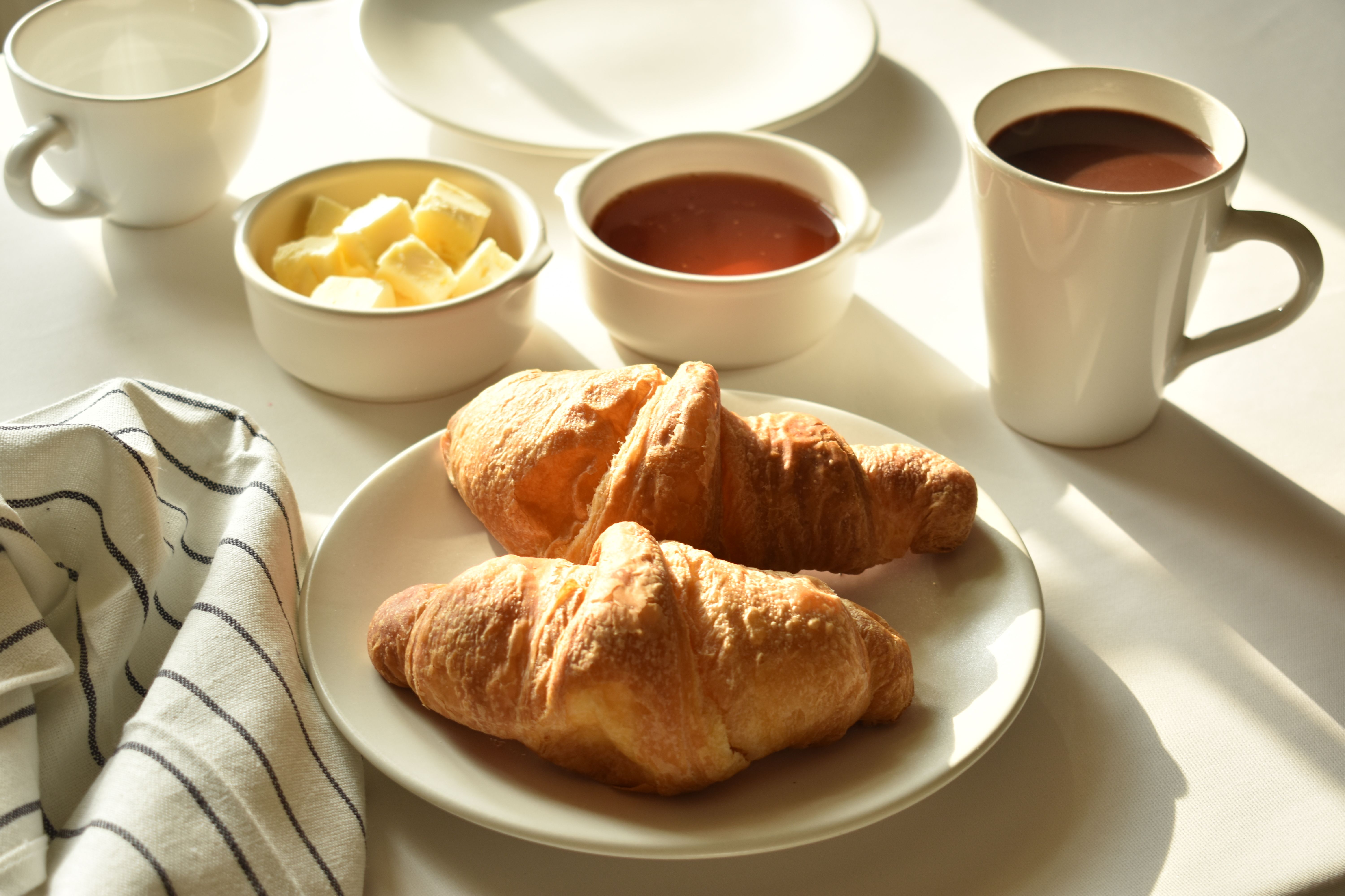 Croissants, beurre, confiture et café sur la table du petit-déjeuner