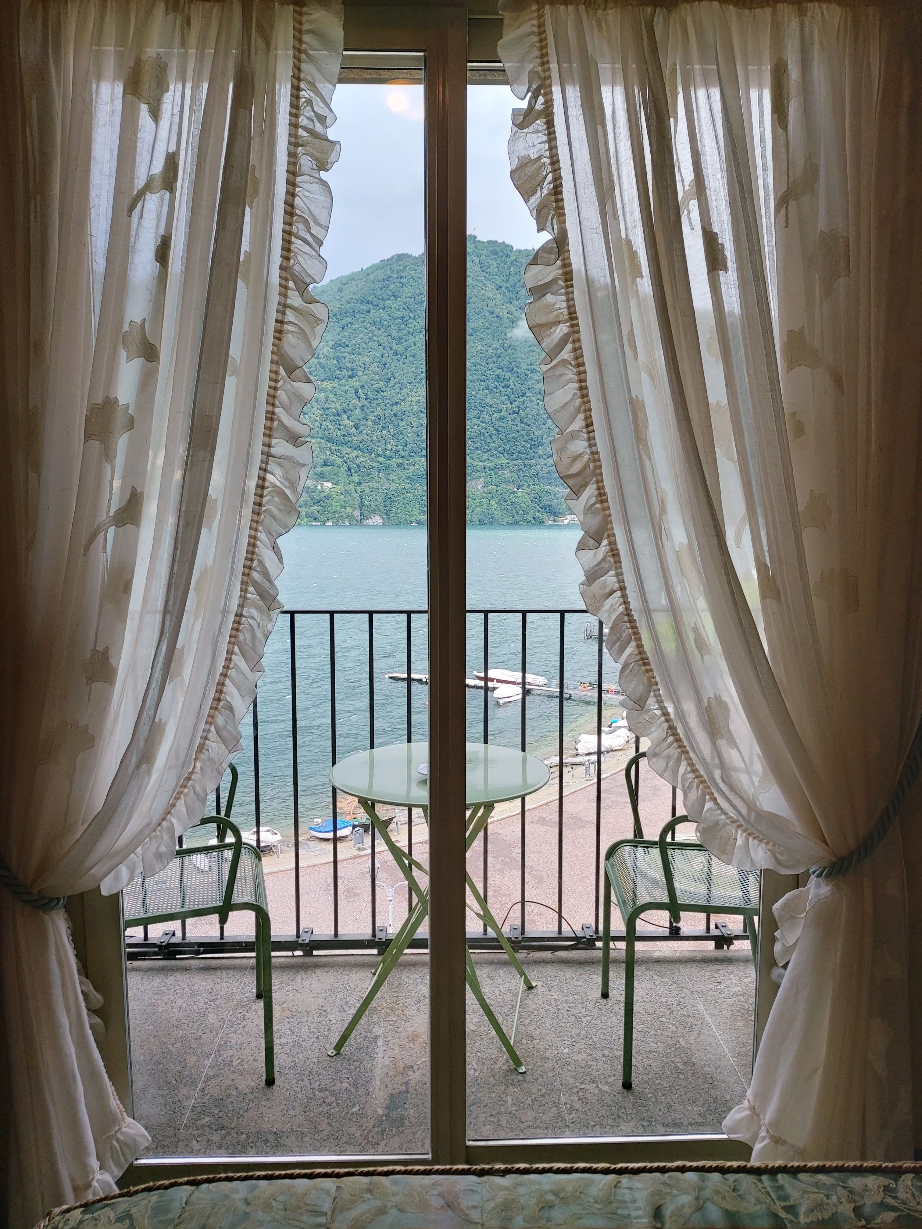 Chambre Vue Lac : rideaux ouverts sur le balcon, le lac et les montagnes