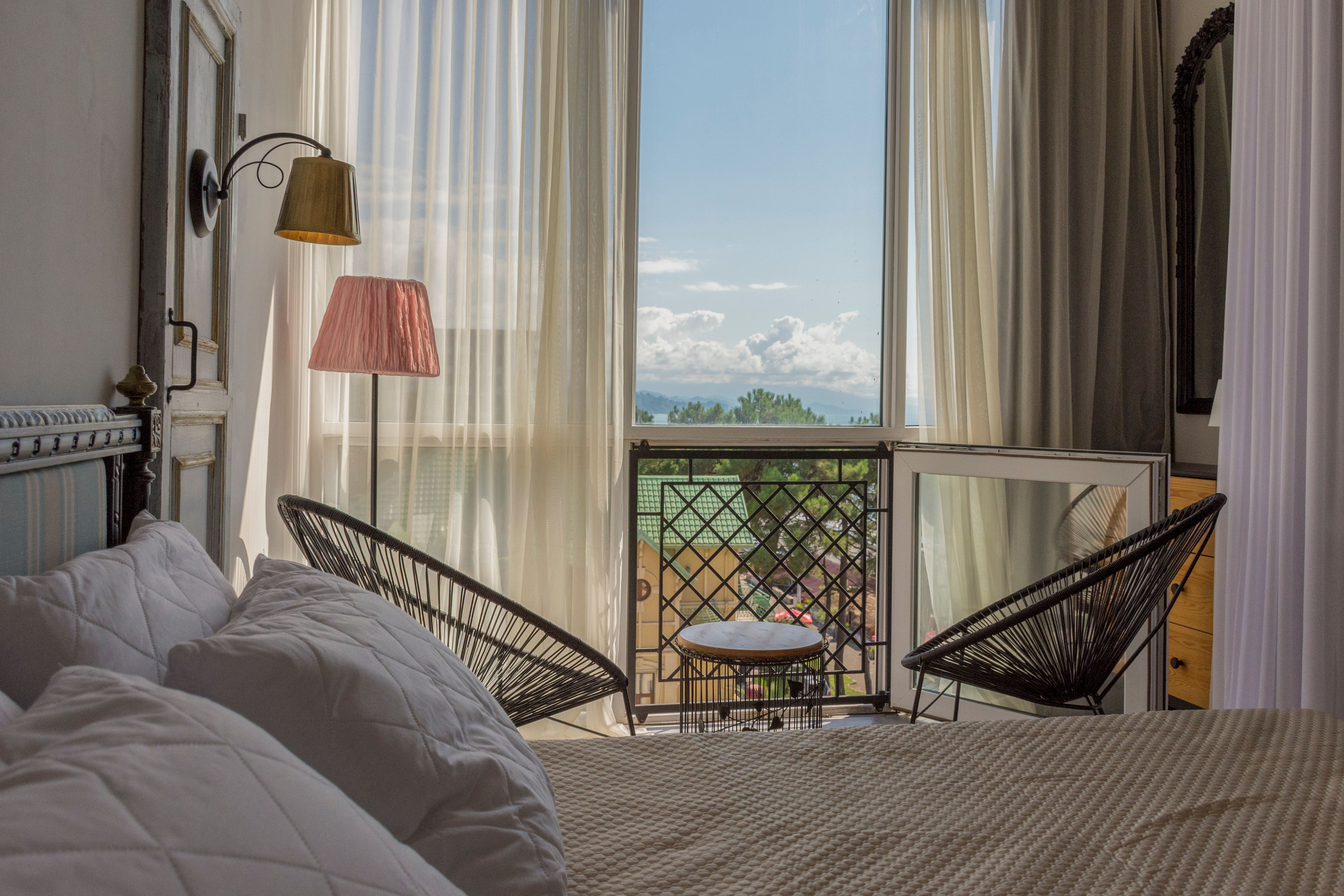 Suite Familiale : grand lit, deux fauteuils et porte-fenêtre ouverte sur la vue